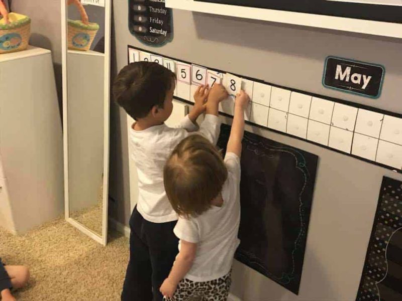 young boy and girl adding number cards to a calendar wall