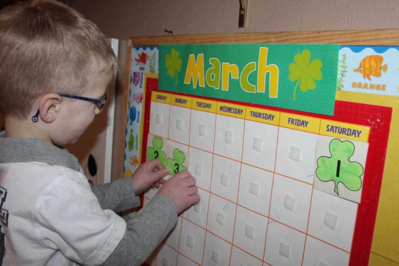 boy with glasses putting numbers on a march calendar