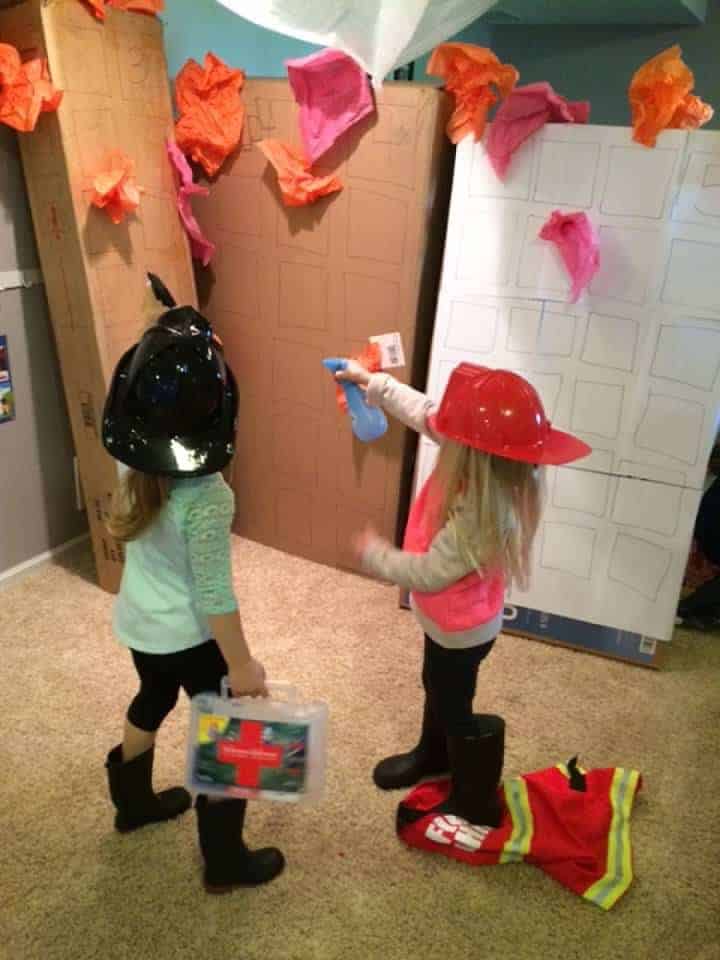 two preschool girls dressed as fire fighters pretending to put out fire