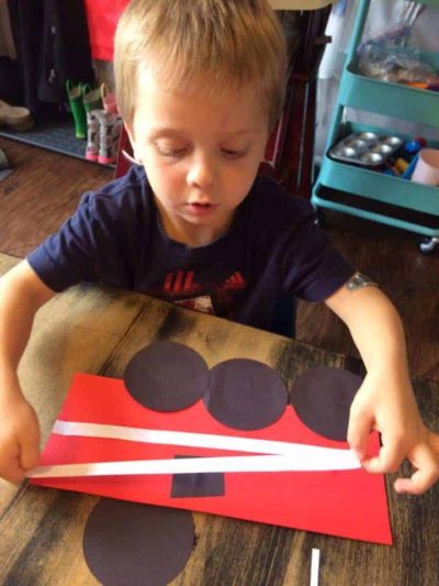 preschool boy creating a firetruck out of paper and glue