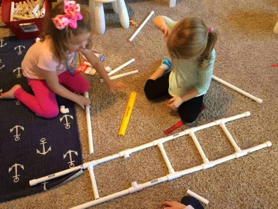 Dos niñas construyendo una escalera con tubos de pvc para la semana de la seguridad contra incendios