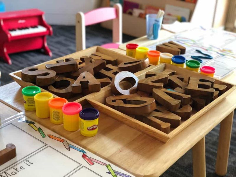 preschool classroom pile of wooden letters and playdoh on a table