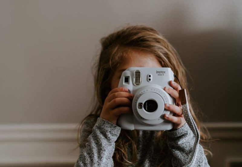 young girl holding a camera up to her face marketing in child care