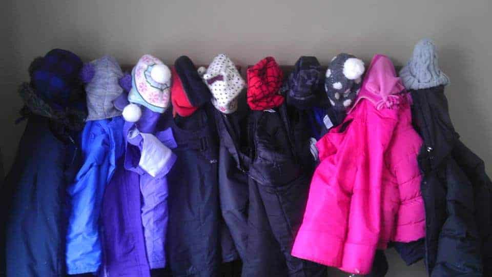 row of winter gear hanging in family child care program