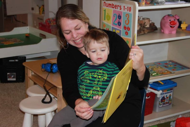 woman with boy in her lap reading a book