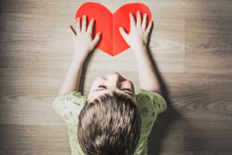 boy holding paper heart on table