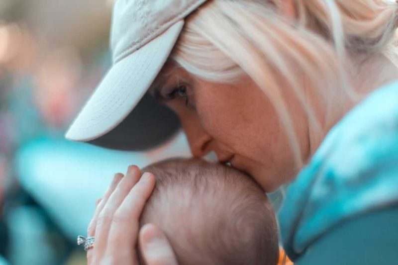 woman in hat kissing baby on head