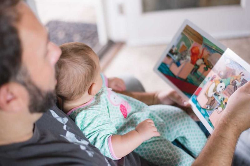 father reading a book to his baby