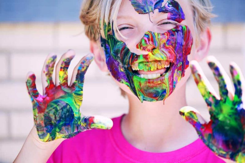 child with paint on face and hands 