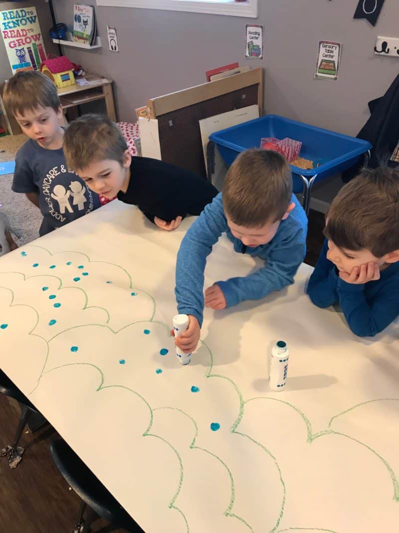 preschool boys stamping blue dot markers onto paper