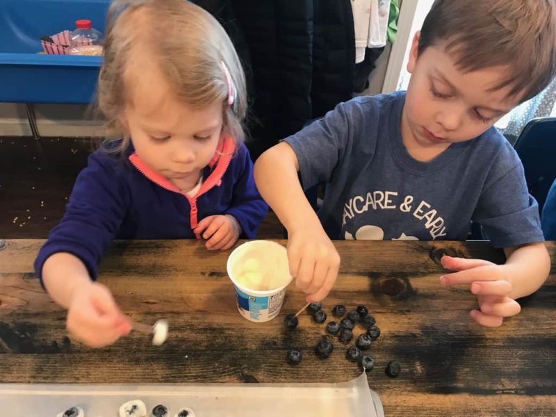 boy and girl dipping blueberries in yogurt