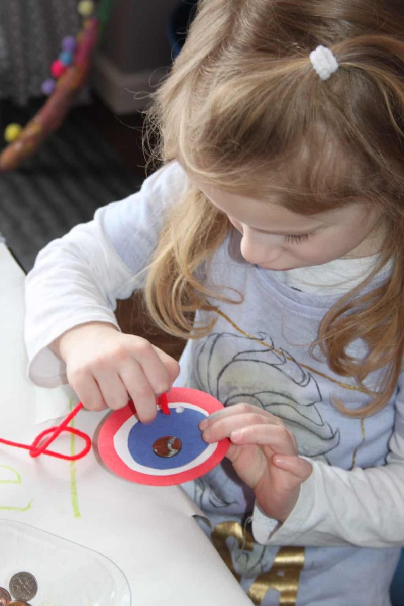 young girl making coin medallion craft to wear on presidents' day