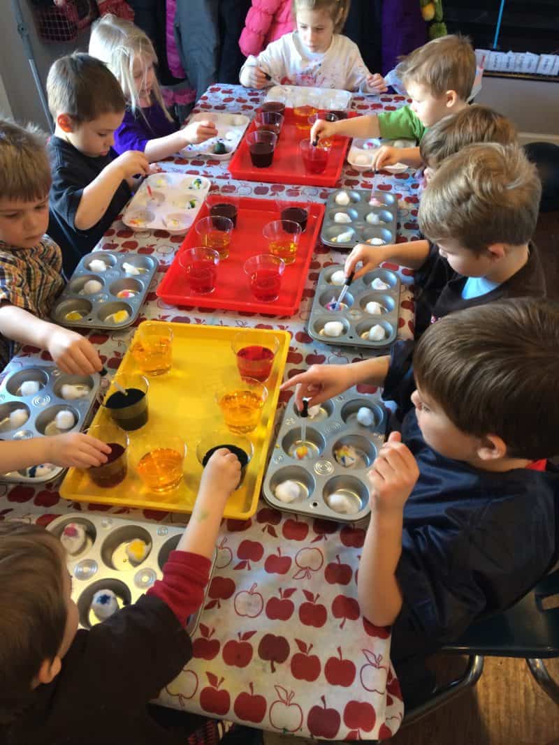 group of young kids playing with color science in trays