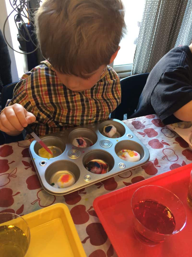 young boy at art table mixing water colors with cotton balls