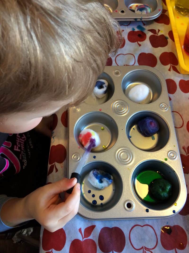 young child mixing water colors muffin tin