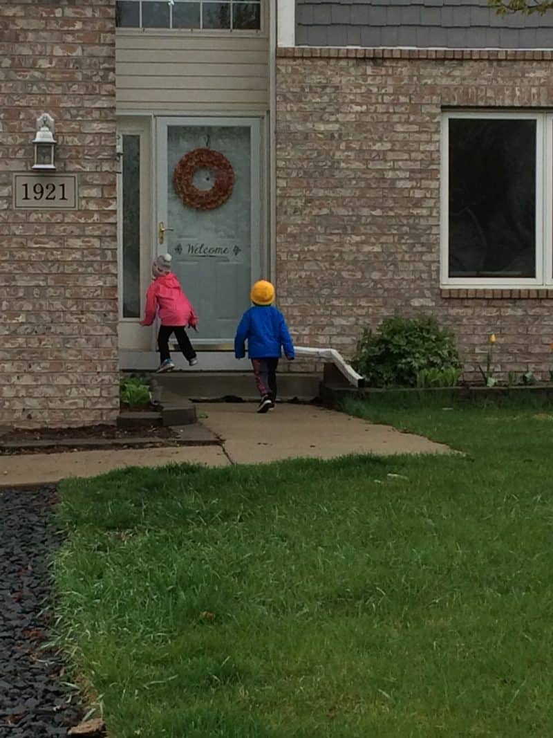 2 young children ringing doorbell on may day with basket