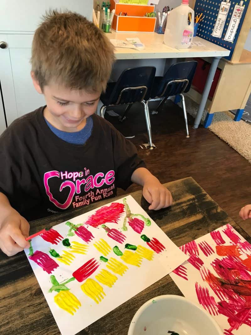 young boy smiling and painting tulips