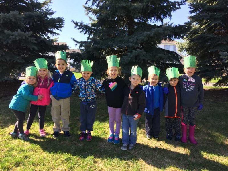 group of preschoolers standing in line wearing paper earth day crowns