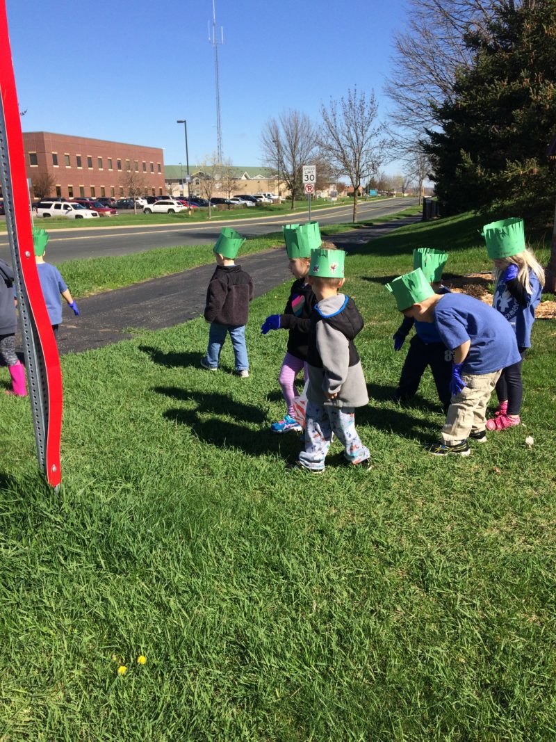 kids wearing paper crowns cleaning up litter for activity to honor earth day