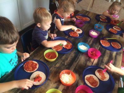 young kids making mini pizzas 