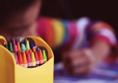 young girl coloring with box of crayons