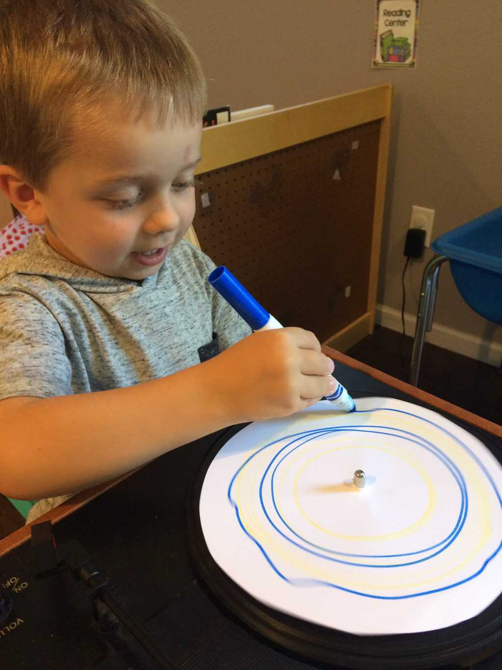 young boy working with record player and marker to make art