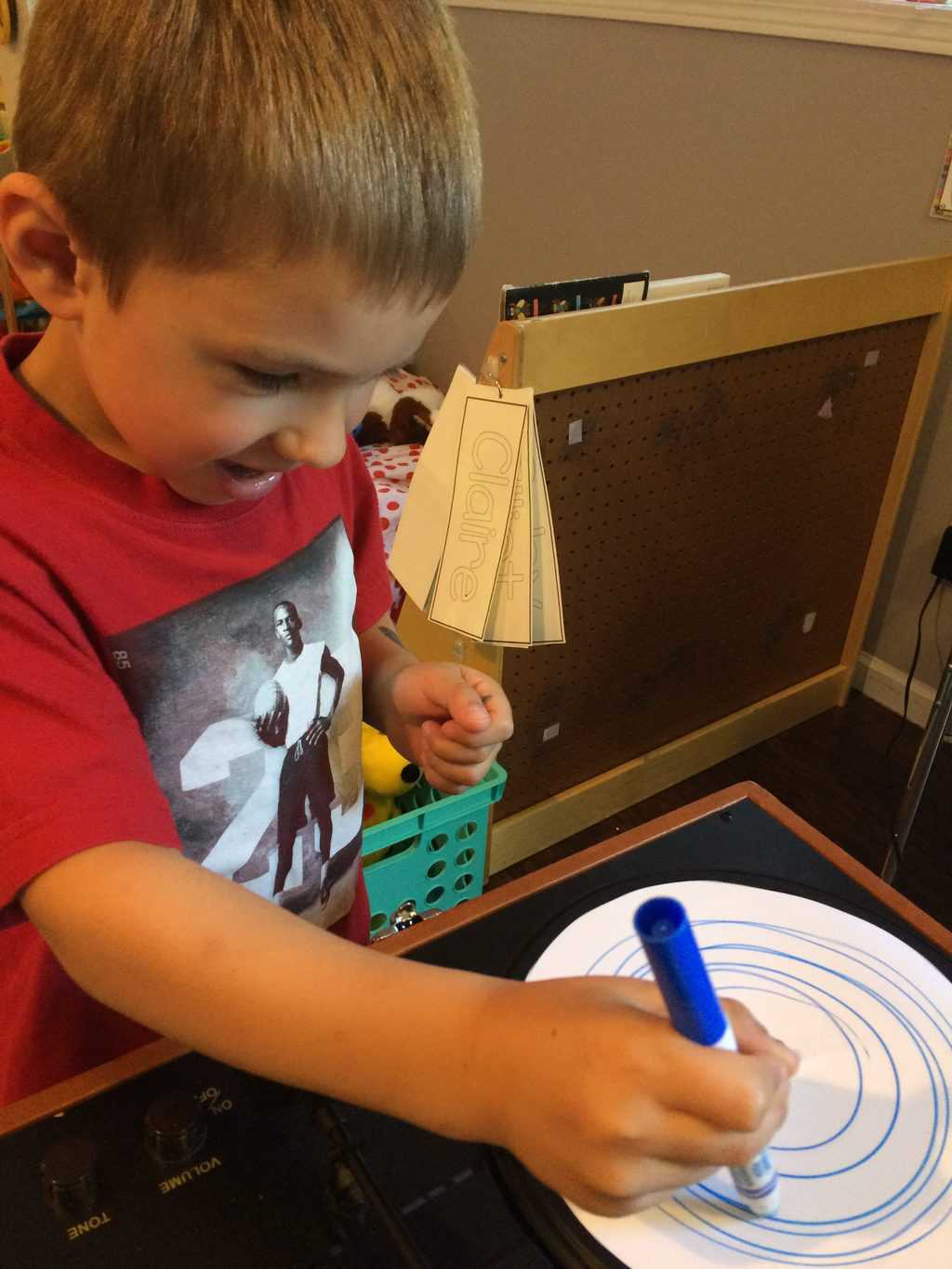 young boy with red shirt using a marker to make circles on paper