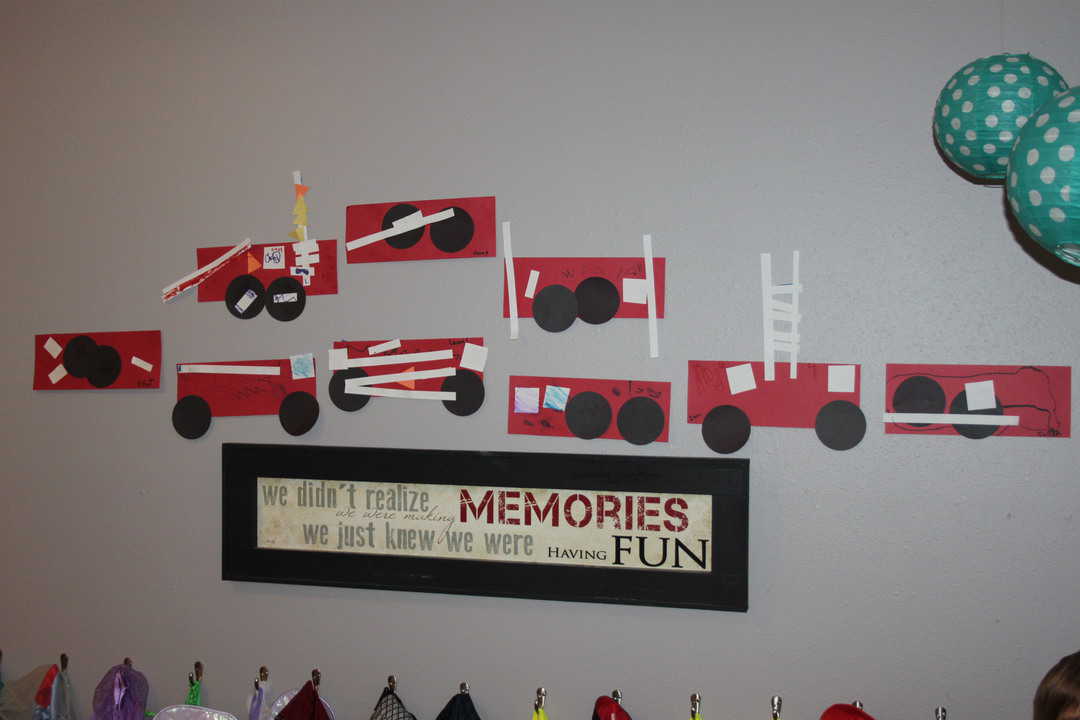 row of homemade paper fire trucks on the wall display for fire safety week