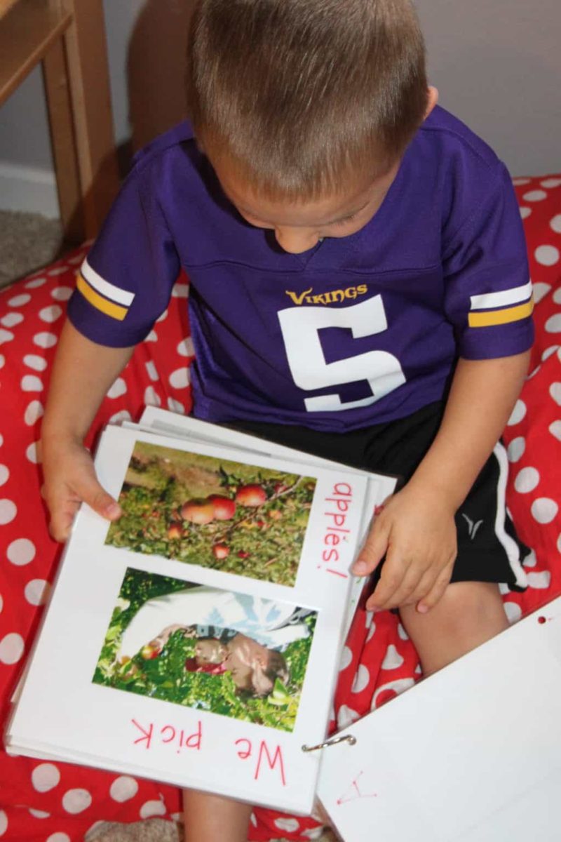 little boy wearing football jersey reading book about apples