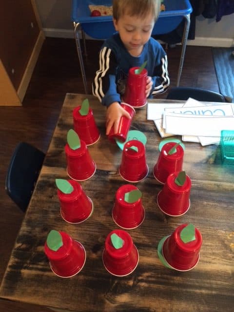 little boy playing with solo cups that look like apples