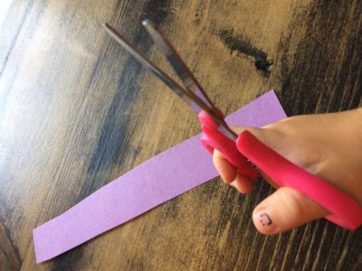 close up of a child's hand holding a scissors with a smiley face on thumb nail