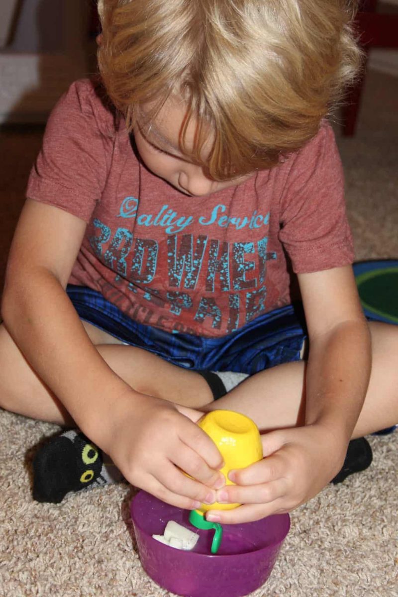 young boy squeezing lemon juice on a bowl of apples