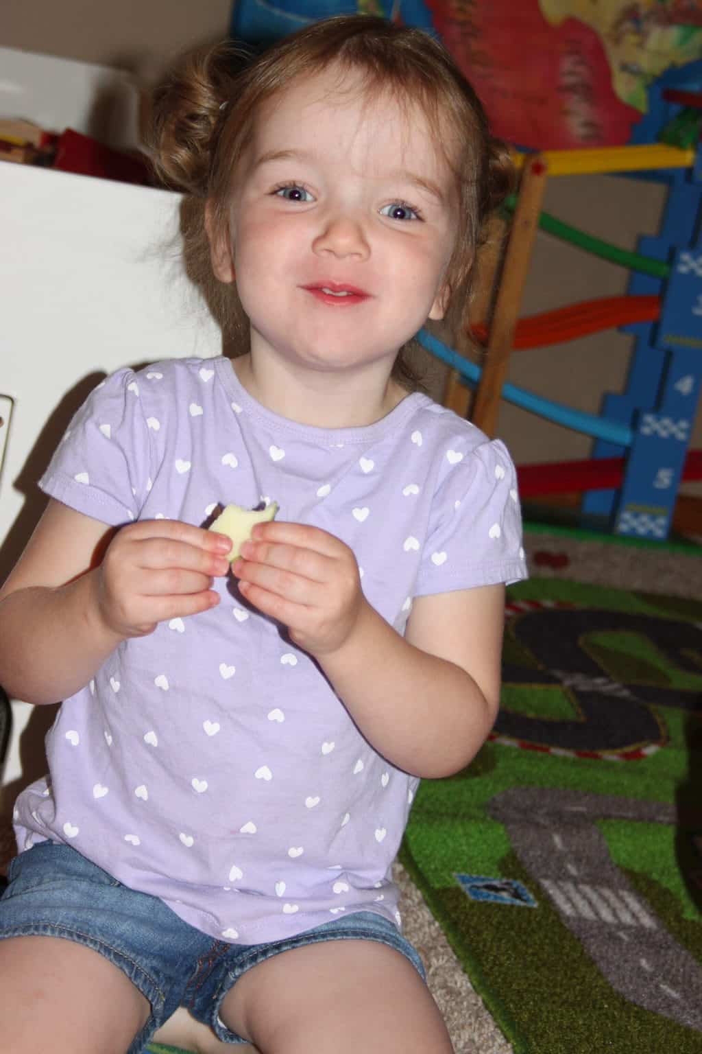 young girl eating an apple slice 