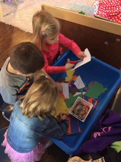 three young kids cutting paper