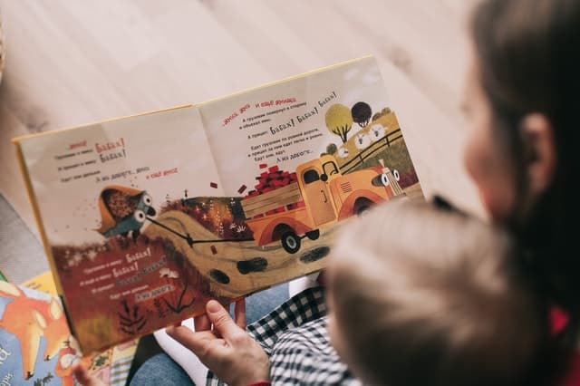 boy reading book with daycare provider